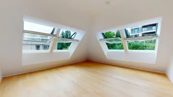 Helles Zimmer im Dachgeschoss mit schrägen Wänden und zwei großen Dachfenstern, die viel Licht hereinlassen.