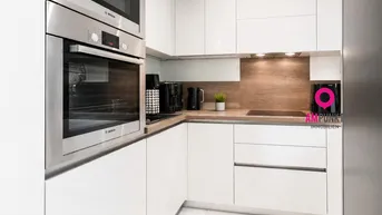 Moderne Einbauküche mit weißen Hochglanzfronten, integrierten Bosch-Geräten und Holzarbeitsplatte.
