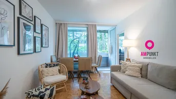 Heller Wohn- und Essbereich mit Parkettboden, gemütlichem Sofa und Zugang zu einem verglasten Balkon.