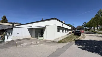 Außenansicht des Gebäudes mit weißer Fassade, grünen Türen und Zufahrt.
