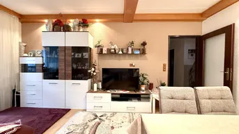 Wohnbereich mit modernem TV-Möbel, Stauraum und Blick auf den Essbereich, funktional und stilvoll.