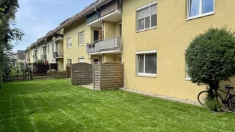 Reihenhausfassade mit gepflegtem Rasenbereich und kleinen Balkonen unter blauem Himmel.