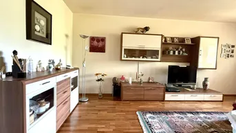 Geräumiges Wohnzimmer mit Holzboden, modernen Möbeln und einem dekorativen Teppich.