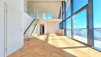 Helles, offenes Wohnzimmer mit Fischgrätparkett, hohen Decken und großen Fensterfronten mit Weitblick.