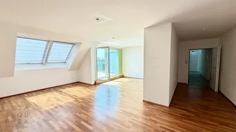 Helles und geräumiges Wohnzimmer mit Holzboden, Dachfenstern und Zugang zu einem Balkon.