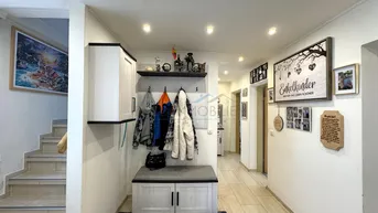 Heller Eingangsbereich mit Garderobe, Sitzbank und Zugang zu Treppe und weiteren Räumen.