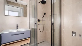 Modernes Badezimmer mit begehbarer Dusche, eleganten Fliesen und einem stilvollen Waschtisch.
