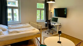 Helles Schlafzimmer mit Holzbett, Schreibtischbereich und Parkettboden, ideal für Wohnen und Arbeiten.