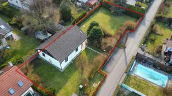 Luftaufnahme eines Einfamilienhauses mit großem Garten und roter Grundstücksumrandung in ländlicher Umgebung.