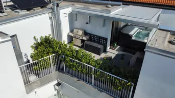 Dachterrasse mit Whirlpool, Grillbereich und üppiger Bepflanzung unter blauem Himmel.