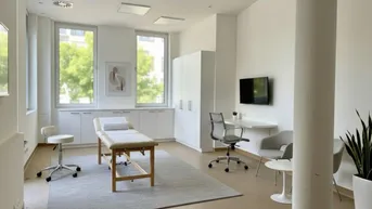 Heller Behandlungsraum mit großen Fenstern, moderner Einrichtung und viel Tageslicht, ideal für Therapien oder Bürozwecke.