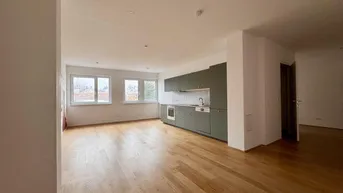 Heller offener Wohn- und Essbereich mit integrierter Küche und Holzfußboden.