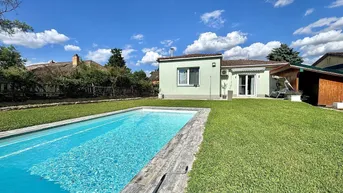 Gepflegter Gartenbereich mit einem erfrischenden Pool und sonniger Liegewiese hinter dem Haus.