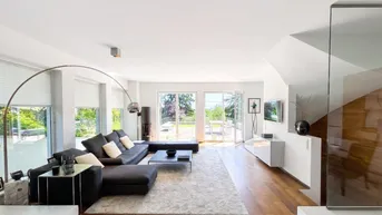Geräumiges Wohnzimmer mit dunklem Sofa, Holzboden und großen Fenstern mit Blick ins Grüne.