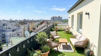 Möblierte Dachterrasse mit Kunstrasen, Pflanzen und weitem Blick über die Stadt.