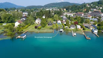 Luftaufnahme von Häusern am Seeufer mit privaten Stegen und üppiger Vegetation.