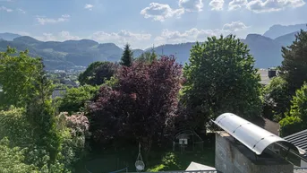 Panoramablick auf die umliegende Berglandschaft und grüne Natur von einem Dach aus.