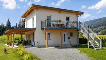 Modernes Einfamilienhaus mit Balkon, überdachter Terrasse und Bergblick in ländlicher Umgebung.