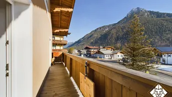 Geräumiger Holzbalkon mit weitem Blick auf die umliegenden Berge und das Tal.