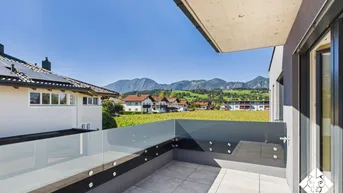 Geräumiger Balkon mit Glasgeländer und weitem Blick auf die umliegende Berglandschaft.
