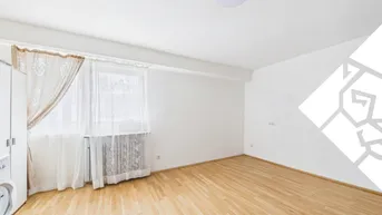 Helles Zimmer mit Parkettboden und einem Fenster, das viel Tageslicht hereinlässt.