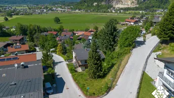 Luftaufnahme einer Wohnsiedlung in ländlicher Umgebung mit beeindruckendem Bergpanorama im Hintergrund.