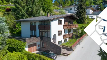 Freistehendes Einfamilienhaus mit Garage, Balkonen und gepflegter Gartenanlage in Hanglage.