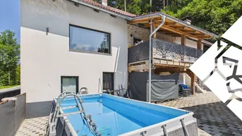 Hausfassade mit einem aufgestellten Pool im Garten und einem Balkon mit dekorativem Geländer.