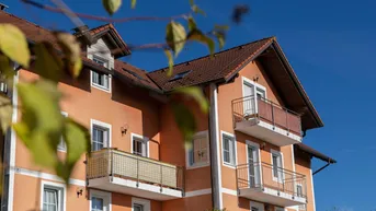 Gebäude mit oranger Fassade, Satteldach und mehreren Balkonen unter blauem Himmel.