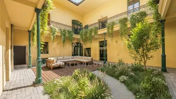 Begrünter Innenhof mit gemütlicher Sitzecke und historischer Architektur, ideal zum Entspannen im Freien.