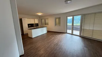 Offener Wohnbereich mit moderner Küche, Kücheninsel und Zugang zur Terrasse mit Bergblick.