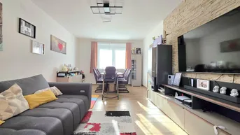 Helles Wohn- und Esszimmer mit modernem Sofa, Esstisch und dekorativer Steinwand.