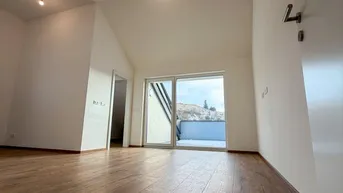 Geräumiger Wohnbereich mit hohen Decken, Holzboden und Zugang zu einem Balkon.