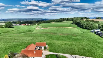 Weitläufige Landschaftsaufnahme mit grünen Hügeln und dem Anwesen im Vordergrund.