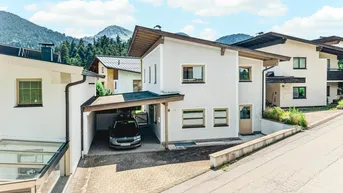 Weißes Einfamilienhaus mit Carport und Bergblick in ländlicher Umgebung.