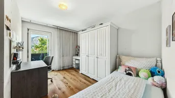 Kinderzimmer mit Einzelbett, weißem Kleiderschrank und Zugang zu einem französischen Balkon.