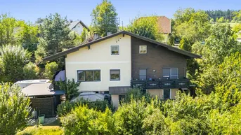 Traditionelles Haus mit Balkonen und umgeben von üppigem Grün in ländlicher Umgebung.