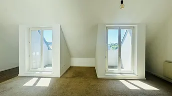 Helles Dachgeschosszimmer mit Teppichboden und zwei Fenstern mit Blick ins Grüne.