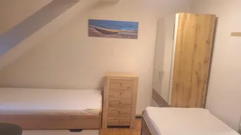 Gemütliches Schlafzimmer im Dachgeschoss mit zwei Einzelbetten, Holzmöbeln und schräger Decke.