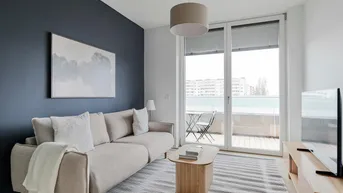 Modernes Wohnzimmer mit beigem Sofa, dunkler Akzentwand und Zugang zum Balkon.