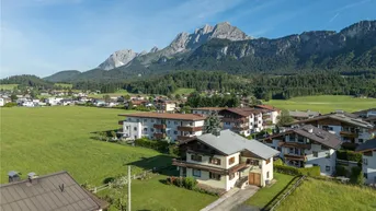 Luftaufnahme eines Hauses in ländlicher Umgebung mit beeindruckendem Bergblick und grünen Feldern.