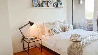 Helles Schlafzimmer mit Holzboden, modernem Bett und direktem Zugang zum Balkon.