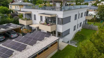 Modernes Mehrfamilienhaus mit Balkonen, Dachterrasse und Photovoltaikanlage auf dem Carport.
