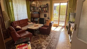 Gemütliches Wohnzimmer mit Ledersofas, Teppichboden und Zugang zu einem Balkon.