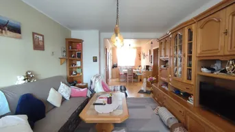 Gemütlicher Wohnbereich mit traditionellen Holzmöbeln und Blick auf den Essbereich.