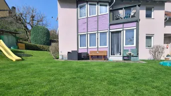 Gepflegter Gartenbereich mit Rasenfläche, Kinderrutsche und einer Terrasse am Haus.