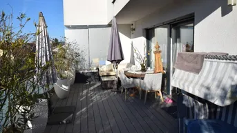 Geräumiger Balkon mit Holzboden, Sitzgelegenheiten und Pflanzen, ideal zum Entspannen im Freien.