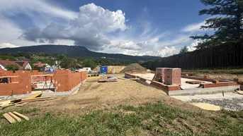 Baustelle mit bereits errichteten Fundamenten und ersten Ziegelwänden für zukünftige Gebäude.