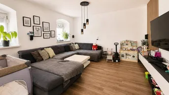Geräumiges Wohnzimmer mit großem Ecksofa, Holzboden und moderner Deckenbeleuchtung, ideal für Familien.