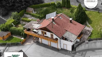 Luftaufnahme eines Hauses mit rotem Ziegeldach, Solarpaneelen und gepflegtem Gartenbereich.